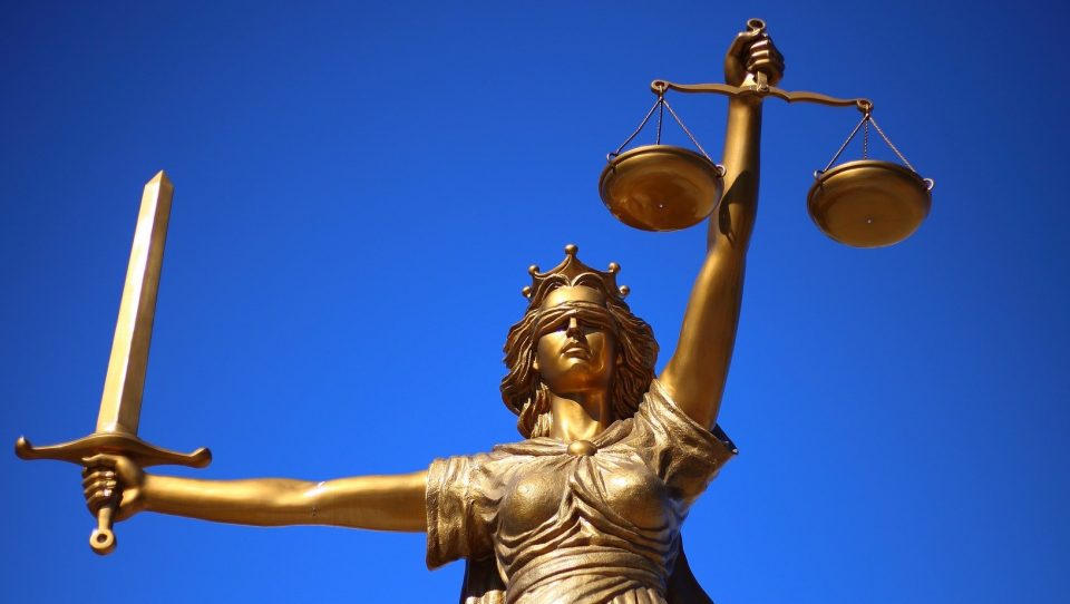 Goldene Justitia-Figur vor blauem Hintergrund