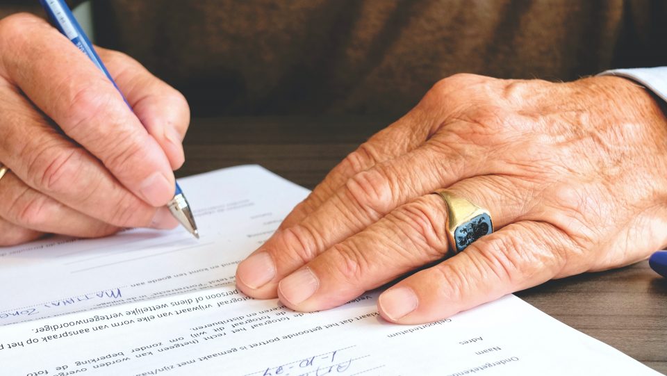 hand älterer person unterschreibt dokument
