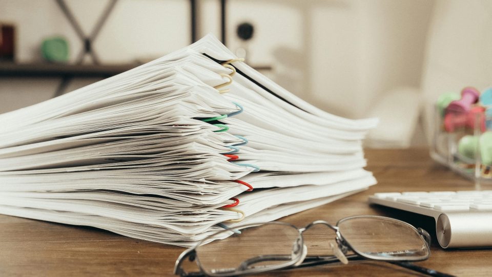 Stapel Dokumente und Brille auf Schreibtisch